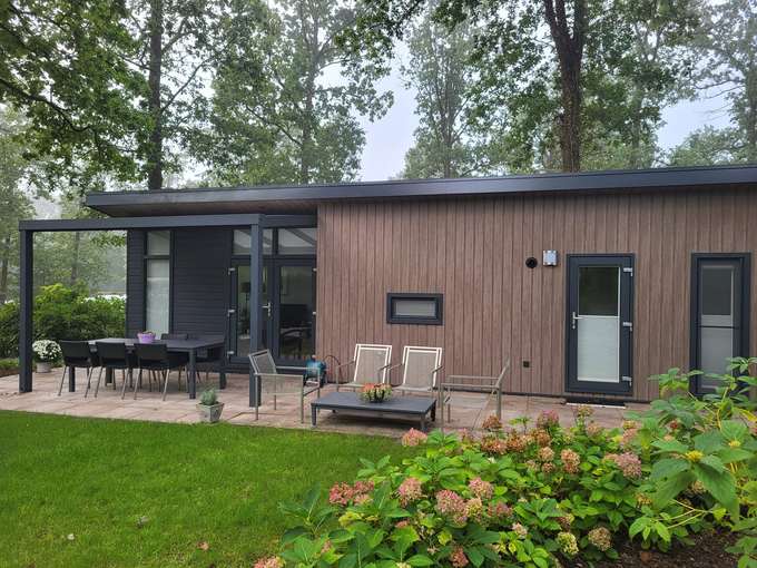 Side view of Chalet Heuvelrug with terrace, lounge area and hydrangeas